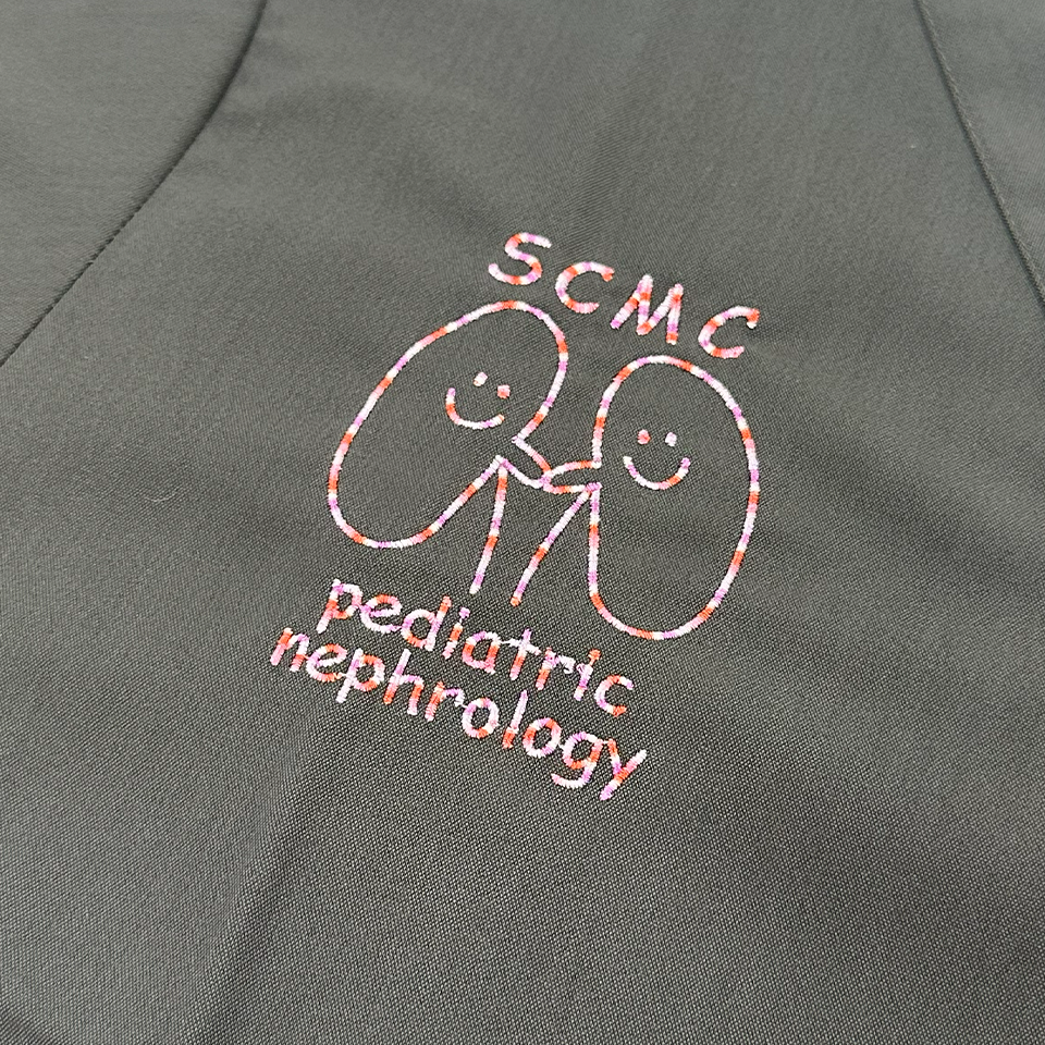 埼玉県立小児医療センター腎臓科のスクラブ。ネイビーとマゼンタの生地に施された右胸のオリジナル刺繍。