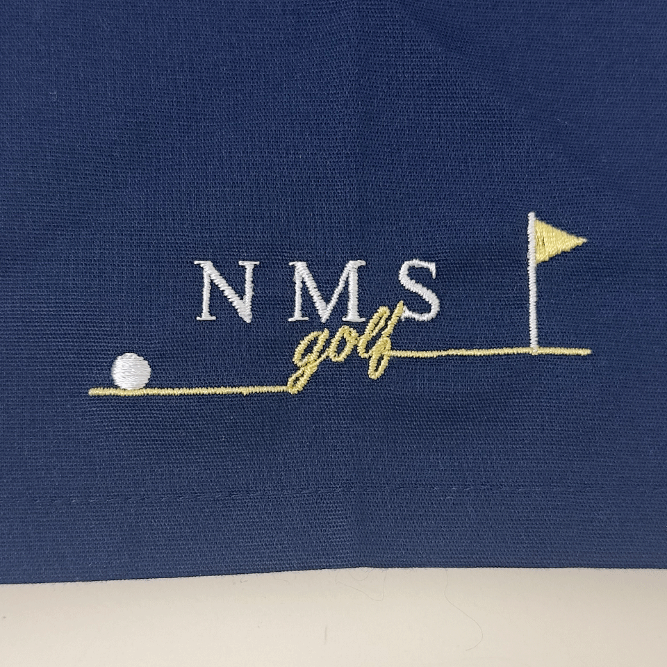 左袖の「NMS golf」ロゴ刺繍。ピンフラッグとゴルフボールのデザインが爽やかなワンポイント。