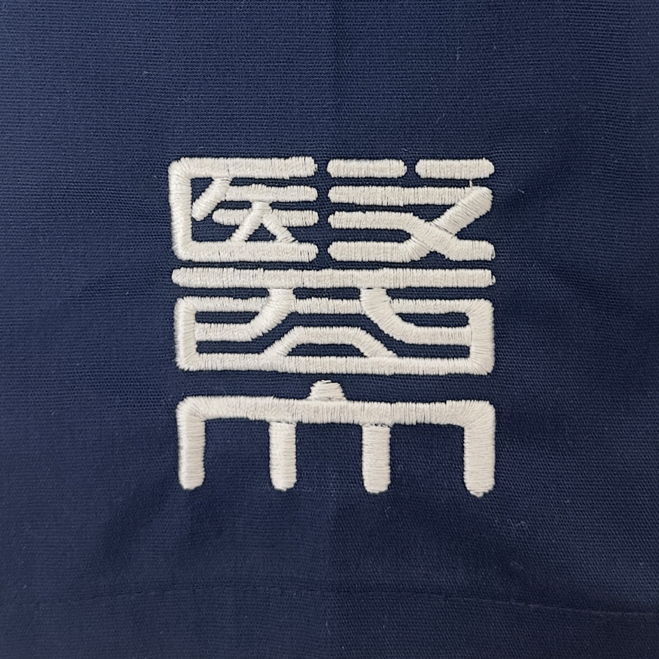 右袖に施された日本医科大学の校章刺繍。白い糸の精密な刺繍でチームの品格を表現。