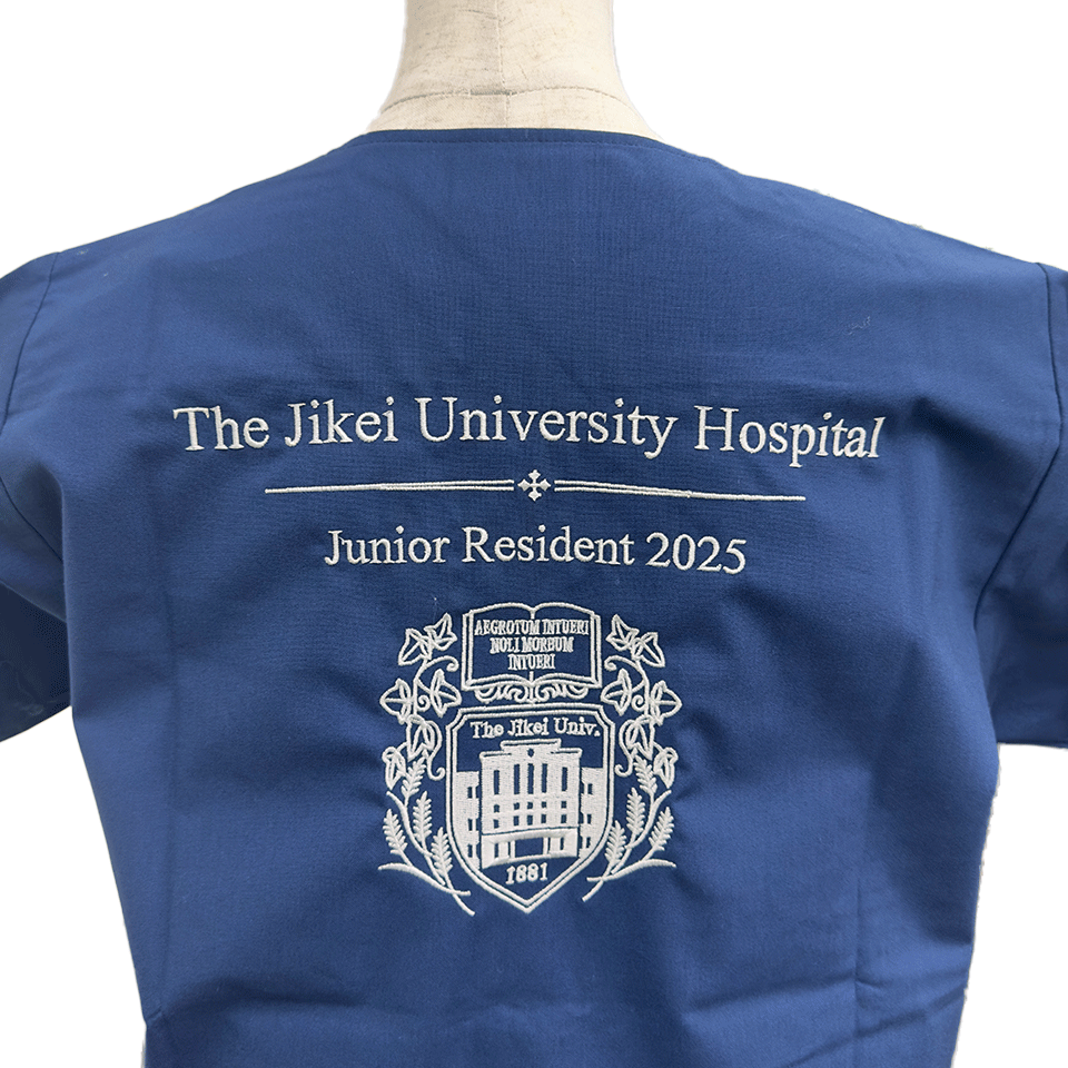 紺地のスクラブに施された、東京慈恵会医科大学附属病院の2025年研修医記念ロゴ刺繍