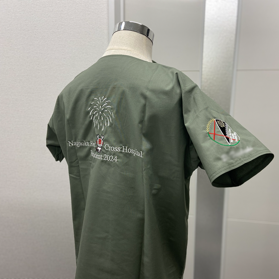 長岡赤十字病院「Resident 2024」の背面刺繍。白い打ち上げ花火の下に、日本赤十字社のキャラクター「ハートラちゃん」がデザインされ、病院名が白文字で刺繍されている。