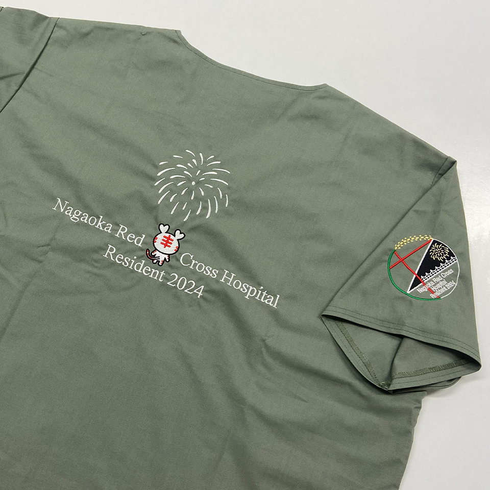 長岡赤十字病院「Resident 2024」の背面刺繍。白い打ち上げ花火の下に、日本赤十字社のキャラクター「ハートラちゃん」がデザインされ、病院名が白文字で刺繍されている。