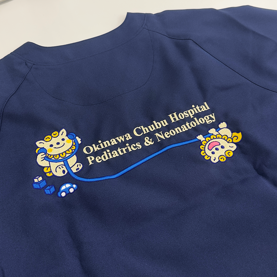沖縄県立中部病院小児科様のオリジナル刺繍。ネイビーの生地に、シーサーと聴診器、英字ロゴが施されています。