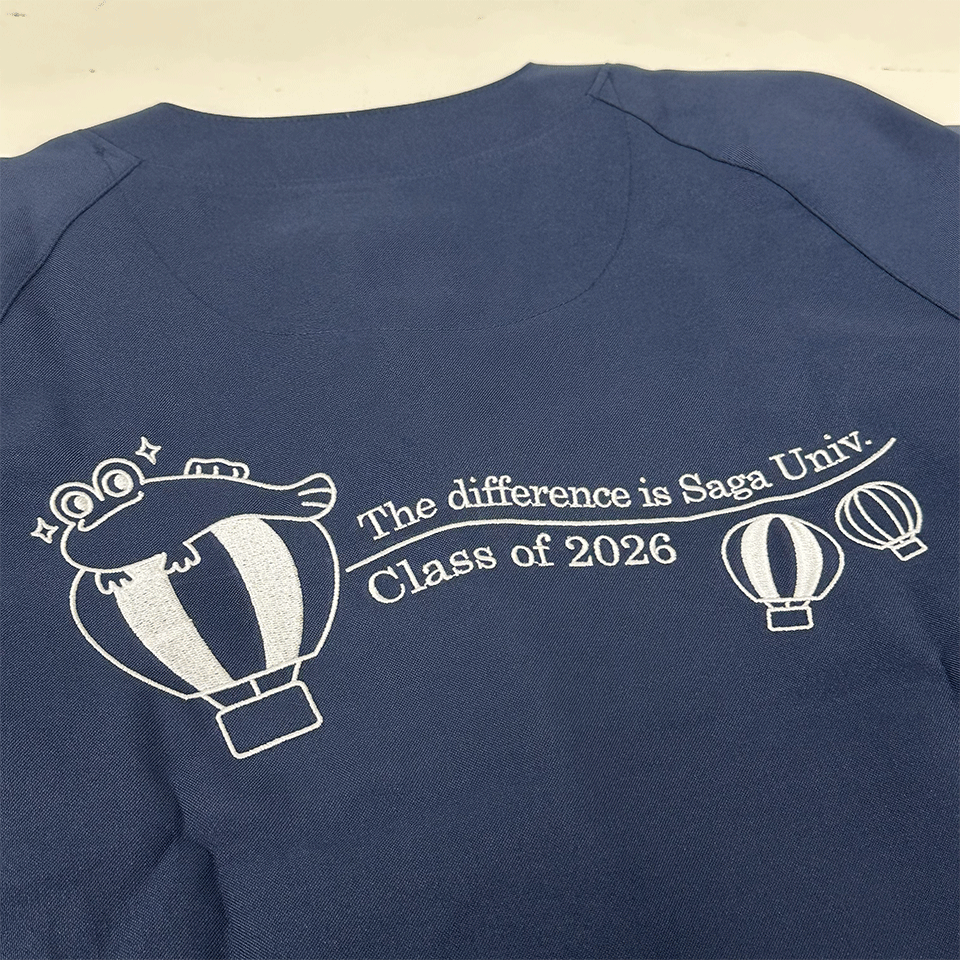 佐賀大学医学部様の刺繍正面デザイン。バルーンにしがみつくムツゴロウの表情やロゴなど、精緻な仕上がりを詳細に示しています。
